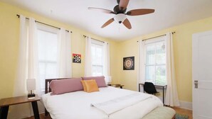 A bedroom with a bed, a desk, a chair, a ceiling fan, and a door. - Gville and Chill House (Gainesville)