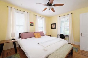 A bedroom with a bed, a desk, a chair, a ceiling fan, and a door. - Gville and Chill House (Gainesville)
