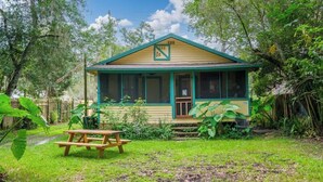 A single-story house with a porch, surrounded by lush greenery. - Gville and Chill House (Gainesville)