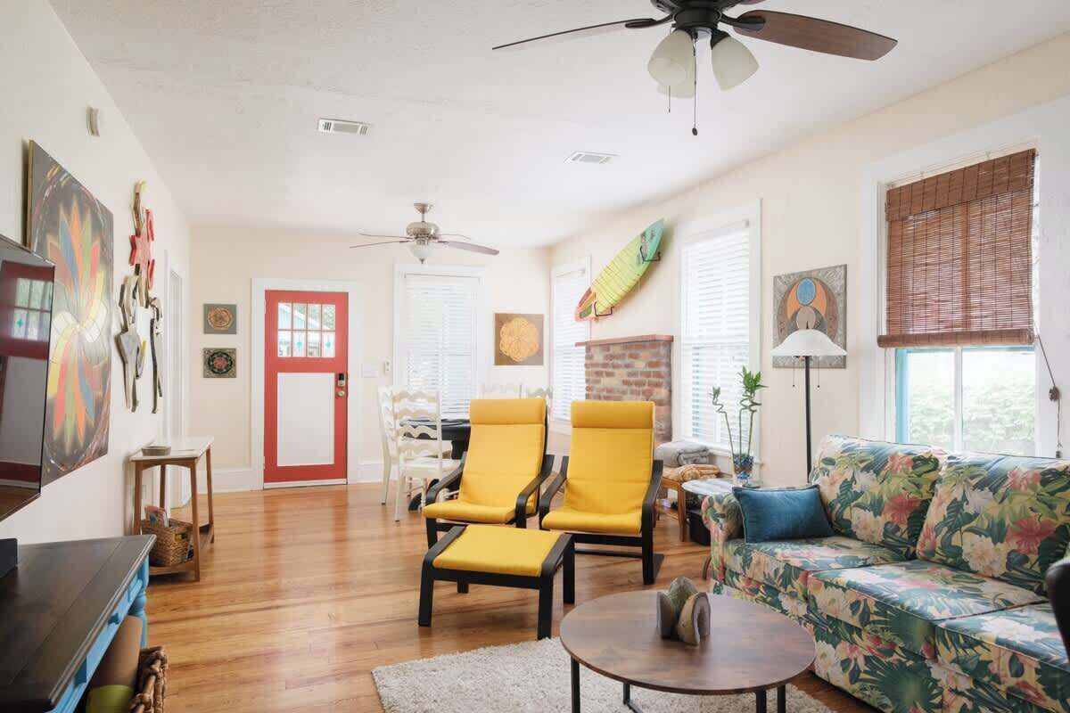 A living room with a sofa, two yellow chairs, a coffee table, and a ceiling fan.