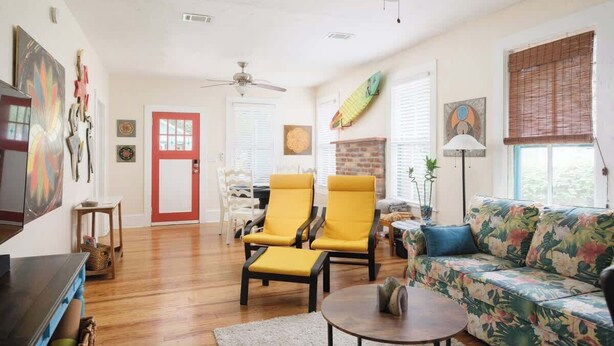 A living room with a sofa, two yellow chairs, a coffee table, and a ceiling fan. - Gville and Chill House (Gainesville)