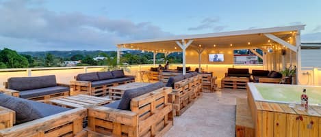 An outdoor seating area with wooden furniture and a bar.
