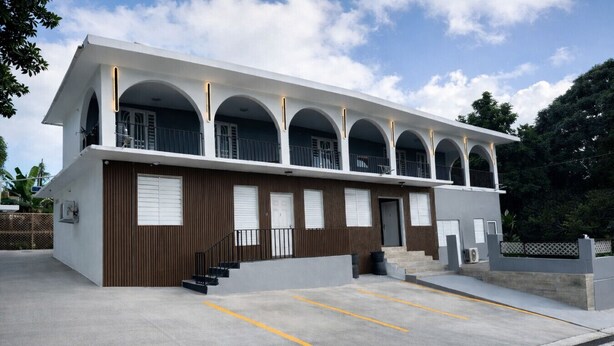 A modern building with a flat roof, multiple balconies, and a parking area. - Top Floor Gem | Huge Balcony + Parking + Nature (Ceiba)