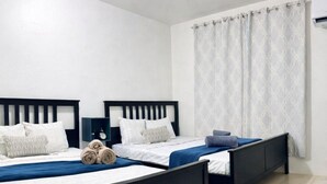 A hotel room with two beds, a nightstand, a clock, and a window with curtains. - Top Floor Gem | Huge Balcony + Parking + Nature (Ceiba)