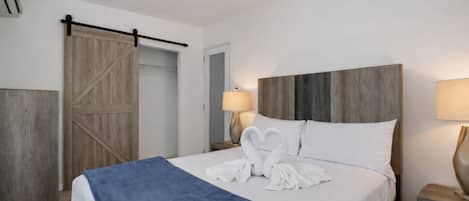 A hotel room with a bed, a nightstand, a lamp, a wardrobe, and a sliding door.