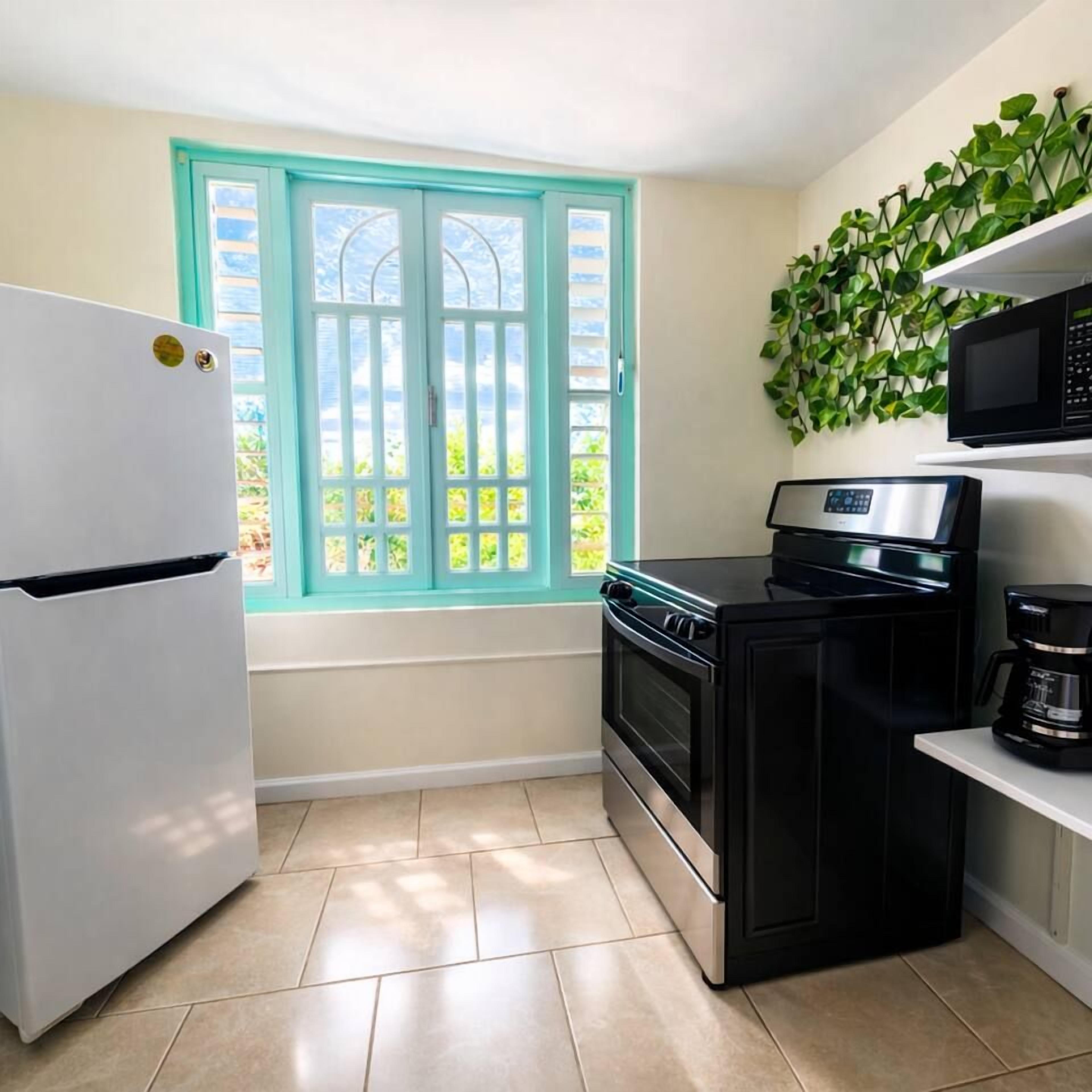 A kitchen with a white refrigerator, black stove, and microwave.