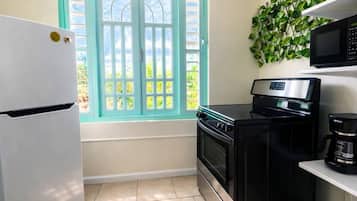 A kitchen with a white refrigerator, black stove, and microwave.