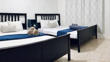 A hotel room with two beds, a nightstand, and a window with curtains.