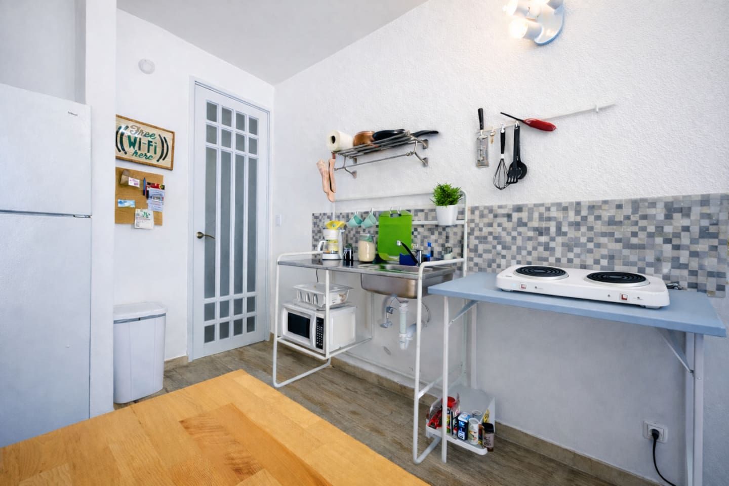 A compact kitchen with a microwave, stove, and various utensils on the wall.