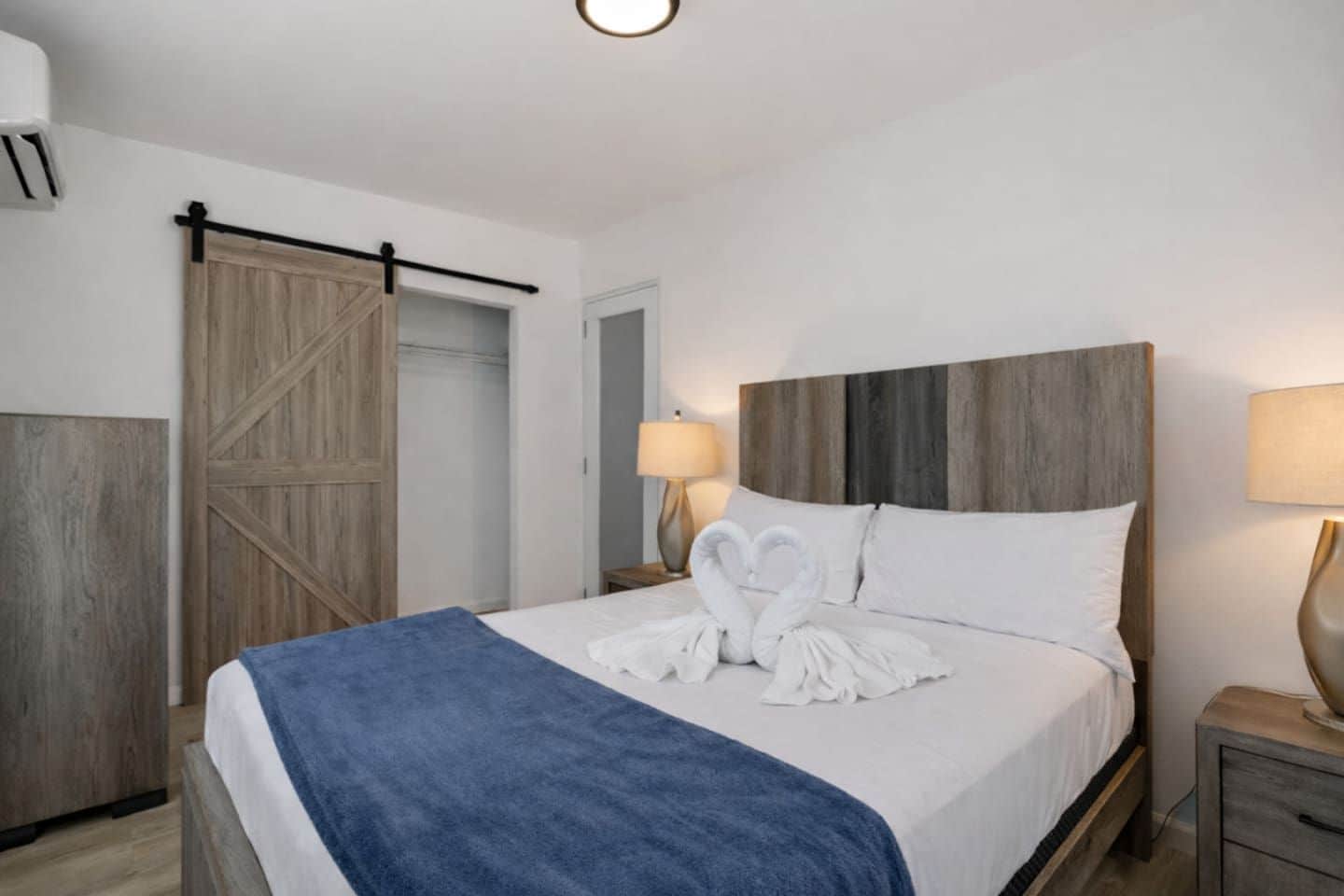 Habitación de hotel con cama, mesita de noche, lámpara, armario y puerta corredera.