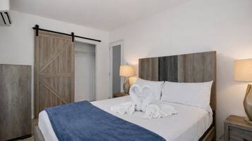 Habitación de hotel con cama, mesita de noche, lámpara, armario y puerta corredera.