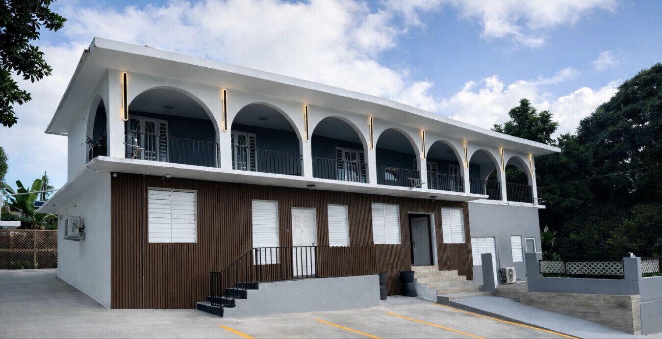 A two-story building with a flat roof, multiple balconies, and a staircase leading to the entrance.