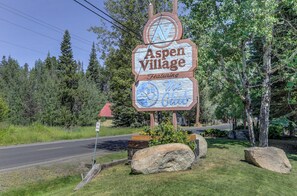Schild für Aspen Village mit einer Bergdarstellung und einem Skisymbol.