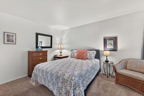 Une chambre à coucher comprenant un lit, une commode, des tables de chevet et une chaise.