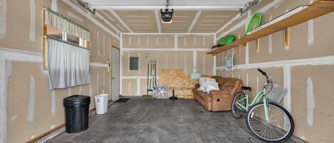 A garage with a concrete floor, a brown sofa, a bicycle, and a fan.