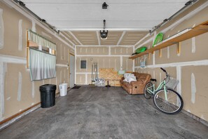 Un garage avec un sol en béton, un canapé marron, un vélo et un ventilateur.