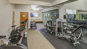 Ett gym med träningsredskap, en bänk och en spegel.