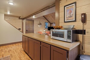 A kitchen with a microwave, a telephone, and a framed poster on the wall. - 16 Pole House - Hot Tub, SHARC Passes, Mountain Getaway (Bend)