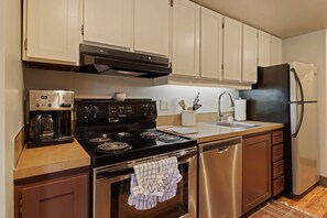 Una cocina equipada con estufa, horno, lavavajillas y refrigerador.