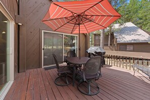 A patio with a table and chairs, an umbrella, and a grill. - 16 Pole House - Hot Tub, SHARC Passes, Mountain Getaway (Bend)