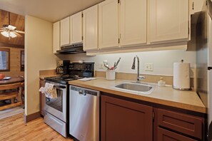 A modern kitchen with stainless steel appliances, wooden cabinets, and a wooden floor. - 16 Pole House - Hot Tub, SHARC Passes, Mountain Getaway (Bend)