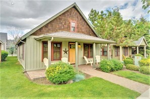 A single-story house with a gabled roof, a front porch with chairs, and a small garden area.
