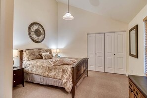Ein Schlafzimmer mit einem Bett, Nachttischen, einem Kleiderschrank, einer Pendelleuchte und einer Wanddekoration.