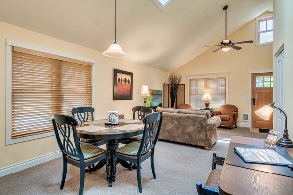 A dining area with a round table and chairs, a sofa, and a ceiling fan.
