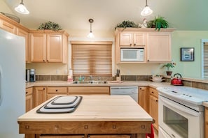 A kitchen with wooden cabinets, a microwave, a sink, and a stove.