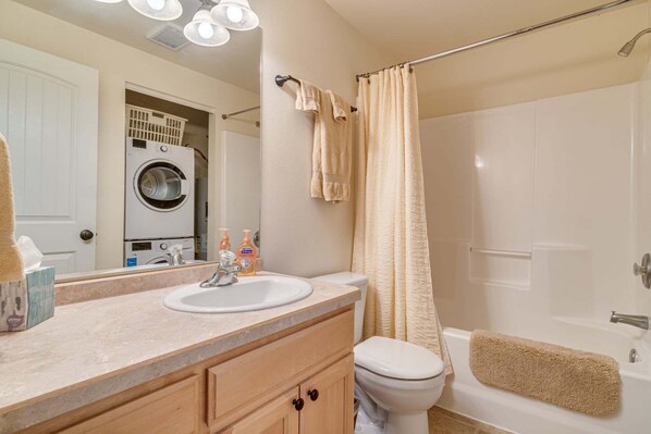 A bathroom with a sink, toilet, and shower area.