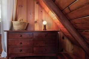 A wooden dresser with drawers and a lamp in a room with wooden walls and a sloped ceiling. - The Writer's Cabin in Lake Arrowhead Woods (Lake Arrowhead)