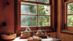 A wooden interior with a window, a table with a teapot, cups, and a plate of cookies. - The Writer's Cabin in Lake Arrowhead Woods (Lake Arrowhead)
