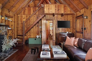 Ein Holzinnenraum mit Treppe, Kamin, Sofa und Fernseher.