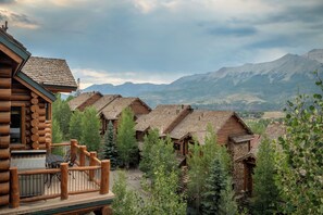 A row of log cabins with a mountain backdrop. - Luxury Mountain Village Retreat | Panoramic Mountain Views | Private Hot Tub | Sleeps 10 (Telluride)