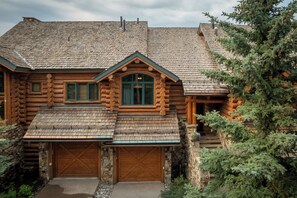 A log cabin with a steeply pitched roof, a central chimney, and a stone foundation. - Luxury Mountain Village Retreat | Panoramic Mountain Views | Private Hot Tub | Sleeps 10 (Telluride)
