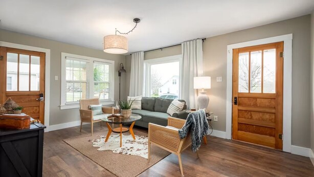 A living room with a sofa, chairs, a coffee table, and a rug. There are two doors, a window, and a ceiling light. - Cozy, Clean, 2-bedroom 1 bathroom home in Lexington, TN (Lexington)