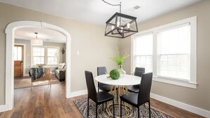 A dining area with a round table, black chairs, a chandelier, and a view of the kitchen through an archway. - Cozy, Clean, 2-bedroom 1 bathroom home in Lexington, TN (Lexington)