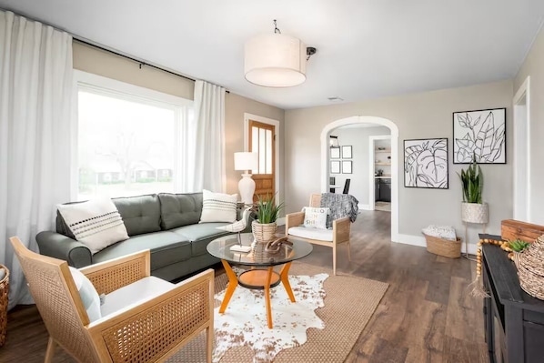 A modern living room with a sofa, chairs, a coffee table, and a view of the outside.