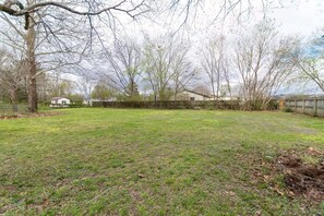 A grassy yard with trees and a house in the background. - Cozy, Clean, 2-bedroom 1 bathroom home in Lexington, TN (Lexington)
