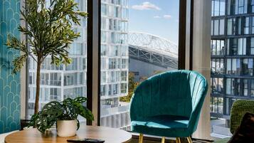 Un intérieur moderne avec un fauteuil recouvert d’un tissu de couleur turquoise, une table ronde en bois et une plante en pot.