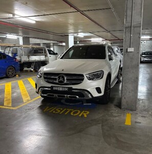 Un parcheggio multipiano con un SUV bianco parcheggiato in una corsia per visitatori.