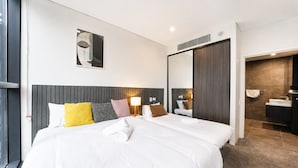 Une chambre d’hôtel avec deux lits, un grand miroir, une salle de bain avec douche et vue sur la ville.