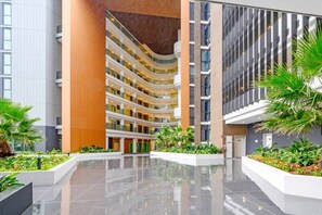 A multi-level atrium with a central open space, surrounded by modern buildings with balconies and reflective floors. - Group stay near Olympic Park & North Strathfield (Homebush)