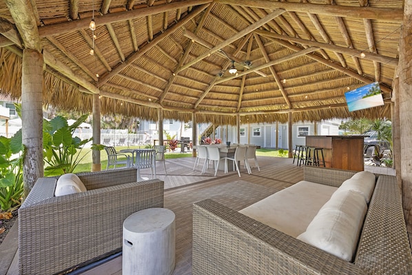 An outdoor seating area with wicker furniture and a thatched roof. - The Eden (Fort Myers Beach)