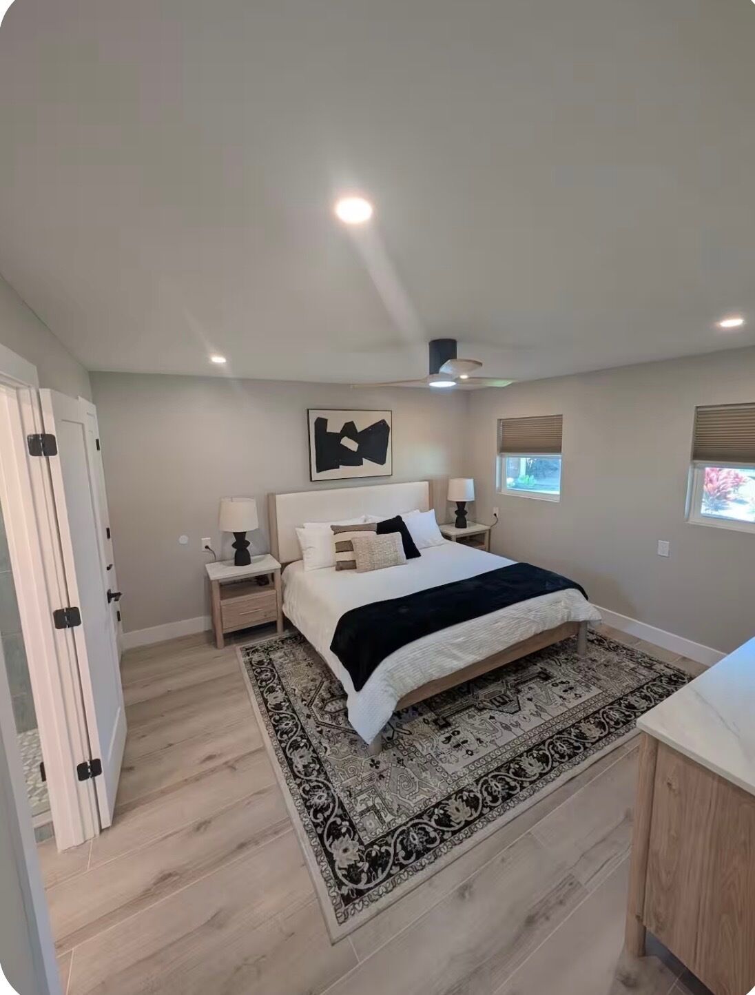Ein Schlafzimmer mit einem Bett, Nachttischen, einem Teppich und einem Deckenventilator.