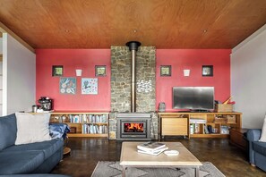 A living room with a fireplace, a television, and a bookshelf. - Petra Villa - Serene Countryside Vistas & Wildlife (Yallingup)