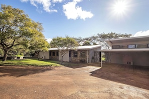 A building with a stone facade, a gravel driveway, and a grassy area with trees. - Petra Villa - Serene Countryside Vistas & Wildlife (Yallingup)
