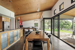 A modern kitchen with a dining area, large windows, and a view of the outdoors. - Petra Villa - Serene Countryside Vistas & Wildlife (Yallingup)