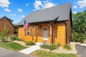 Eine Holzhütte mit grauem Dach, einer Haustür und einer US-amerikanischen Flagge.