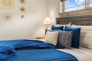 Ein Schlafzimmer mit einem Bett, Kissen, einer Lampe und Wandbildern.
